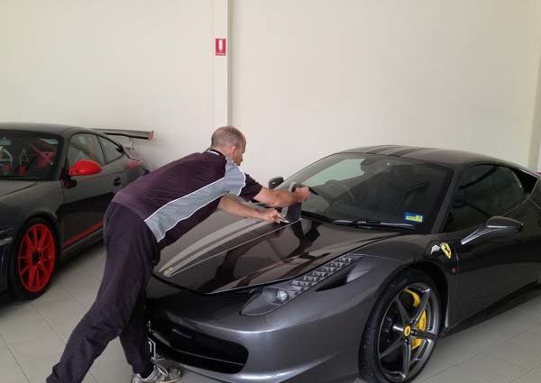 man installing racing stripes on sports car